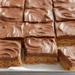 Lunch lady peanut butter bars no-bake retro school cafeteria dessert ready in 15 minutes with 1 cup salted butter cubed 1 cup creamy Jif or Skippy peanut butter microwaved 50% power 30-second increments stirred smooth, 1 teaspoon vanilla added, 2 cups graham cracker crumbs 1.75 cups powdered sugar folded thick dough pressed parchment-lined 9x9 pan refrigerated, 1.5 cups milk or semisweet chocolate chips 2 teaspoons coconut oil microwaved 30-second intervals stirred smooth poured top offset spatula spread even layer, refrigerated 2 hours set sliced 16 squares served