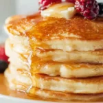 Best fluffy pancakes stack golden brown thick buttermilk pancakes with melting butter dripping maple syrup and fresh berries