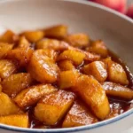 Warm cinnamon fried apples with brown sugar glaze in a cast iron skillet served as a fall dessert