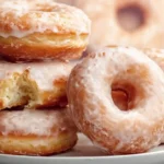 Homemade glazed donuts golden and pillowy soft cooling on a wire rack with a thin shiny vanilla glaze dripping down their sides