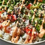 California Roll Sushi Bowls with a bed of seasoned sushi rice topped with creamy crab mixture cucumber avocado nori sesame seeds and sriracha mayo drizzle