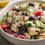 Mediterranean Chicken Salad with grilled chicken lettuces chickpeas tomatoes cucumbers olives red onions feta cheese avocado and lemon herbs in a bright bowl